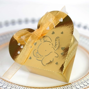 Scatola regalo cuore dorata con stampa elefante e nastro elegante posta su un piatto