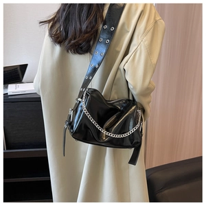 Detail of glossy black shoulder bag featuring silver chain and metal eyelet strap