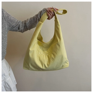 Close-up of bright yellow tote bag featuring MVICHI embroidery and soft fabric texture