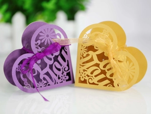 Detail of laser-cut heart candy boxes in purple and yellow with For You text and silk ribbons