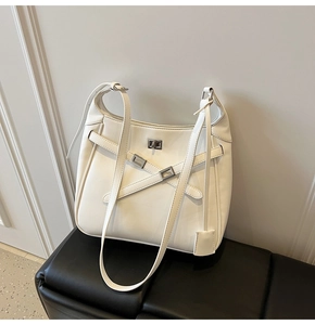 Close-up of white leather bucket bag with crisscross straps and silver twist-lock closure