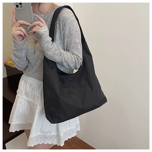 Close-up of black shoulder tote bag featuring MVICHI letter embossing and fabric texture