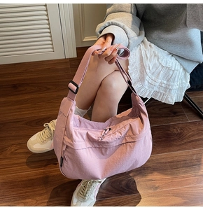 Détail du sac bandoulière croissant en nylon rose clair avec texture et sangle large