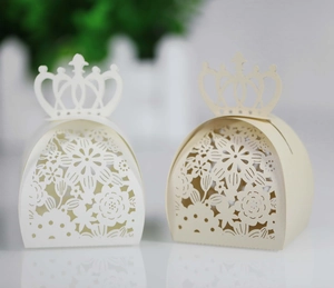 Detailed laser-cut crown favor boxes in white and beige paper for wedding party gifts