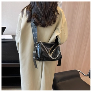 Detail of black patent leather crossbody bag with silver chains and wide eyelet shoulder strap