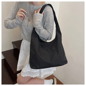 Detail view of black nylon tote bag with embossed logo and wide shoulder strap