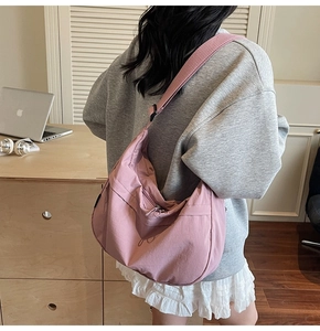 Détail macro d'un sac demi-lune en nylon rose pâle montrant la texture et la tirette nouée