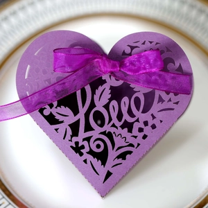 Macro detail of purple laser-cut heart favor box with Love script and satin bow