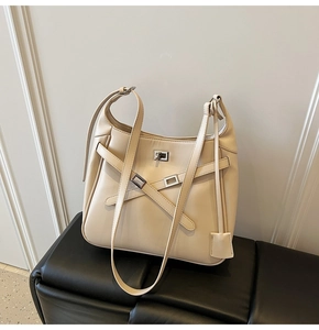 Close-up of beige crossbody bucket bag featuring cross-strap design and silver metal buckle