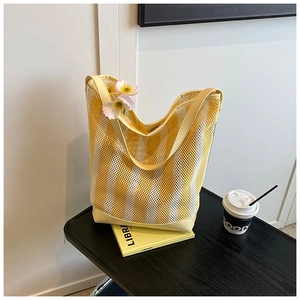 Détail du sac cabas en maille rayée jaune avec base en cuir renforcée sur fond noir