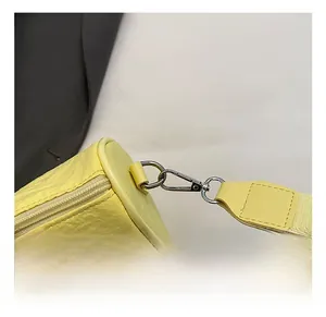 Detailed close-up of the silver metal hook and litchi texture on yellow crossbody bag