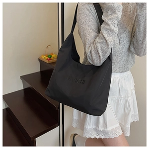 Detail of minimalist black hobo bag showing embossed MVICHI logo on matte nylon fabric