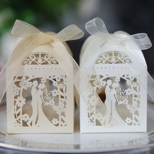 Macro detail of laser-cut hollow candy boxes featuring bride and groom with silk ribbons