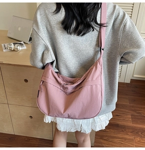 Détail du sac croissant en nylon rose avec large bandoulière et texture plissée souple