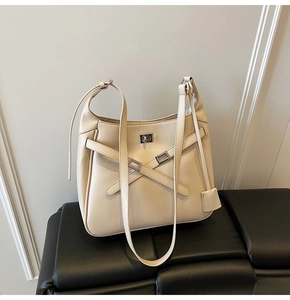 Detail of beige bucket bag with silver metal buckle and cross strap on black bench