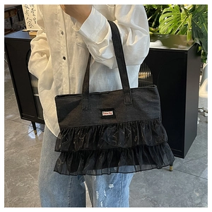 Detail of black denim tote bag featuring layered mesh ruffles and Fashion Bag label