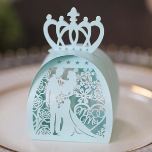 Close-up of laser-cut light blue wedding candy box with Mr & Mrs crown design on a plate