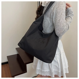 Detailed close-up of the black nylon tote bag showing the textured fabric and strap design