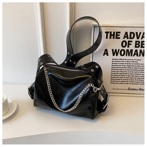 Close-up of black glossy pillow bag with chunky silver chain and eyelet strap detail