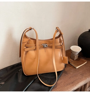 Detail of caramel leather bucket bag with silver twist lock and retro decorative straps
