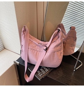 Détail du sac à bandoulière rose en nylon montrant la texture plissée et la sangle réglable