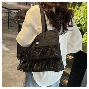 Detail of black denim tote bag featuring tiered lace ruffles and Fashion Bag label