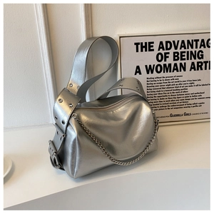 Detail of silver metallic shoulder bag with eyelet studded strap and decorative chain
