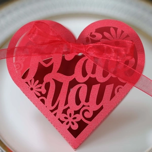 Close-up of red heart-shaped wedding favor box with laser-cut I Love You text and ribbon