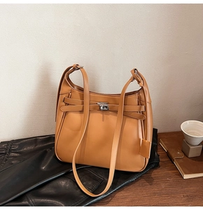 Detail view of a caramel leather hobo bag with metallic lock and decorative straps