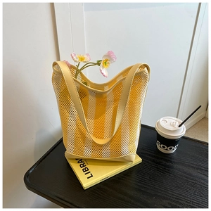 Détail du sac cabas en maille à rayures jaunes et blanches avec poignée et base en cuir