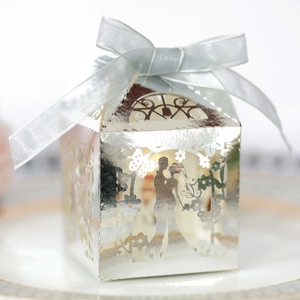 Close-up of laser-cut wedding favor box with romantic silhouette and blue silk ribbon