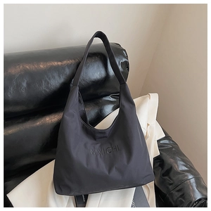 Close-up of the MVICHI logo embossing on a black nylon tote bag with wide strap detail