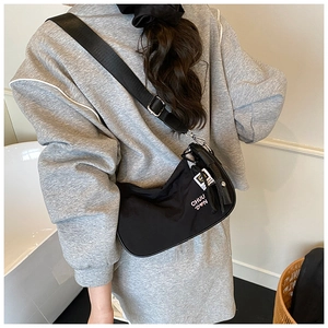 Rear view of black nylon crescent crossbody bag with adjustable wide strap on model