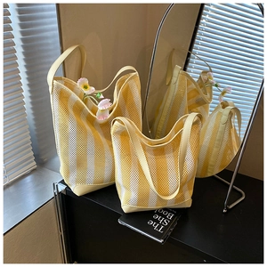 Vue détaillée des sacs fourre-tout en maille à rayures jaunes et blanches avec bordure cuir
