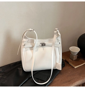 Detail view of white leather bucket bag with silver twist lock and strap accents