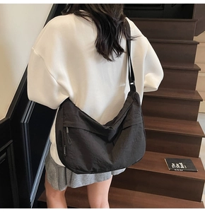 Gros plan détaillé d'un sac bandoulière noir en nylon avec large sangle sur un modèle