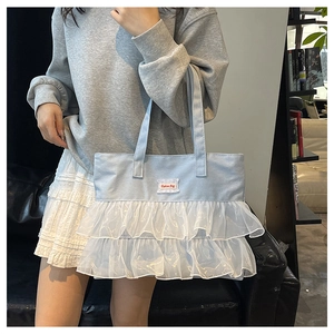 Detail of light blue denim tote featuring white lace pleats and Fashion Bag woven label