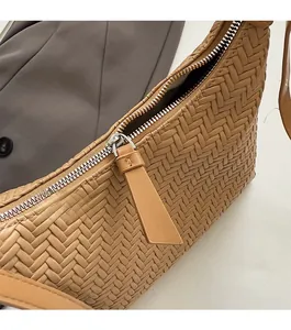 Detail of woven texture and smooth metal zipper on light brown dumpling shoulder bag