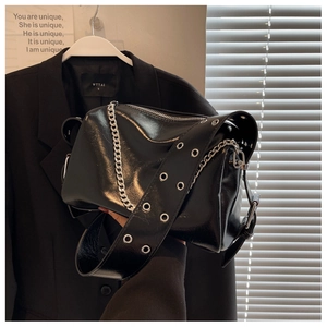 Detail of black glossy PU leather crossbody bag with silver chains and eyelet strap