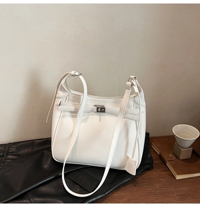 Detailed close-up of a cream white minimalist shoulder bag with a silver twist lock closure