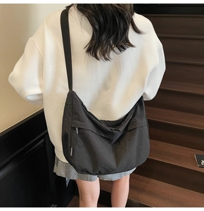 Vue portée d'un sac bandoulière noir en forme de croissant avec sangle réglable