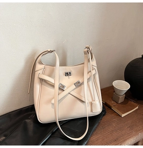 Detail of off-white leather bucket bag with silver metal buckle and cross-strap design