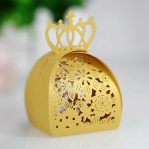 Macro view of golden laser-cut wedding favor box with intricate hollow floral patterns