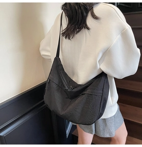 Détail d'un grand sac croissant en nylon noir avec poches zippées porté par un mannequin
