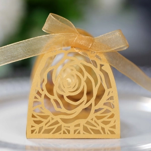 Dettaglio del motivo a rosa intagliato al laser su scatola regalo dorata con nastro