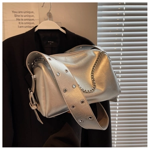 Detail view of silver metallic pillow bag with wrinkled texture and wide eyelet strap