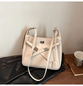 Close-up of minimalist beige bucket bag with silver square twist lock and cross strap detail