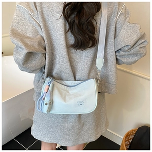 Detail view of light blue crossbody bag with adjustable wide fabric strap and zipper