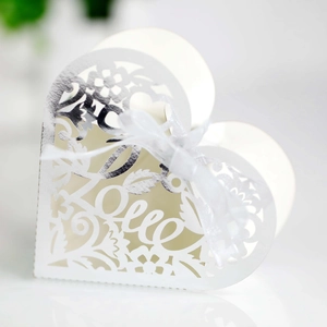 Close-up of white heart wedding candy box with laser-cut LOVE text and white silk ribbon