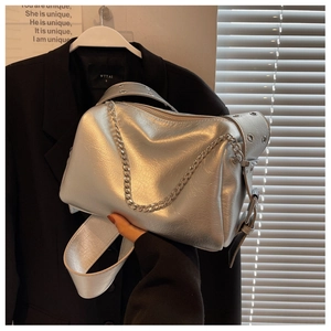 Detail of silver metallic pillow bag with chunky chain strap and punk style grommet belt